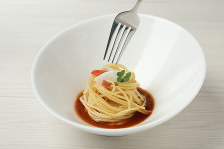 Eating tasty spaghetti with sauce from at white wooden table, closeup. Exquisite presentation of pasta dishの写真素材
