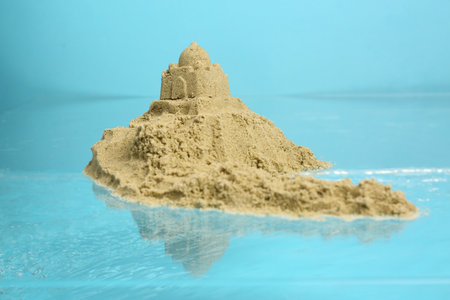 Pile of sand with sultan's palace near rippled water against light blue background. beautiful castle