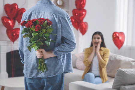 Man hiding bouquet of red roses for his beloved woman, closeup. Valentine's day celebrationの写真素材