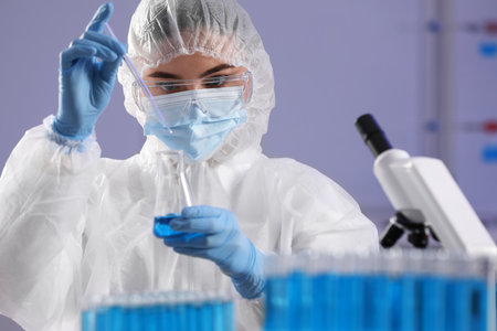 Scientist taking sample of light blue liquid in laboratory