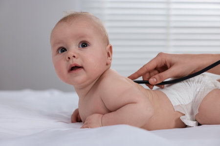 Pediatrician examining cute little baby with stethoscope in clinic, closeupの写真素材