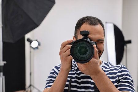 Professional photographer taking picture in modern photo studio, space for text