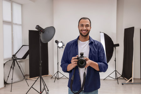 Young professional photographer with camera in modern photo studio, space for text