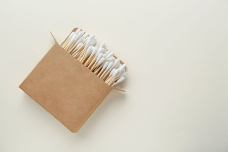 Box with wooden cotton buds on beige background, top view. Space for textの写真素材