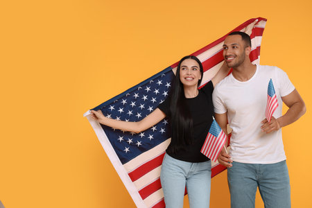 4th of July - Independence Day of USA. Happy couple with American flags on yellow background, space for textの写真素材