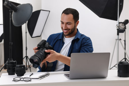 Young professional photographer with camera at table in modern photo studioの写真素材