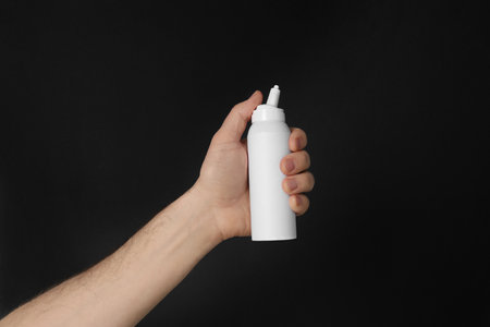 Man holding nasal spray on black background, closeupの写真素材