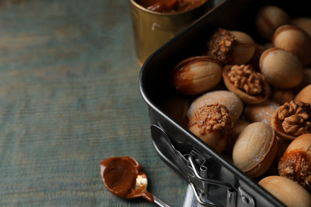 Freshly baked homemade walnut shaped cookies and boiled condensed milk on wooden table, closeup....