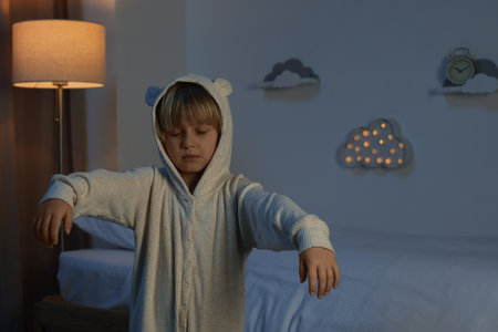 Boy in pajamas sleepwalking indoors at nightの写真素材