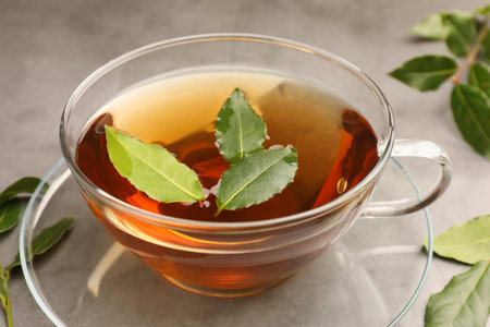 Cup of freshly brewed tea with bay leaves on gray table, closeupの写真素材