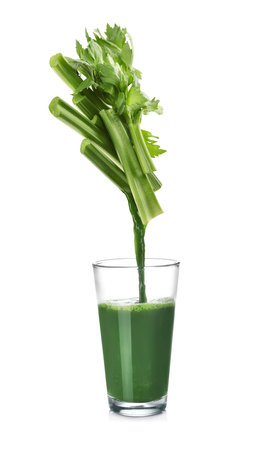 Pouring freshly squeezed juice from celery into glass on white backgroundの写真素材