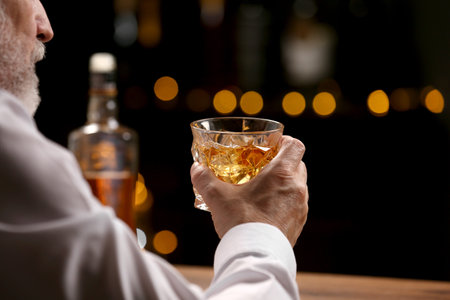 Senior man with glass of whiskey at bar counter, closeup