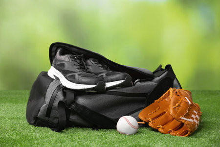 Bag and different sports equipment on grass against blurred backgroundの写真素材