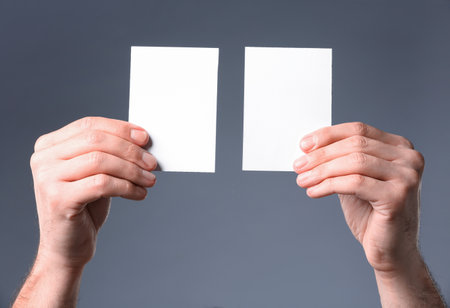 Man holding paper cards on gray background, closeup. Mockup for designの写真素材