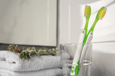 Two light green toothbrushes in glass holder indoorsの写真素材