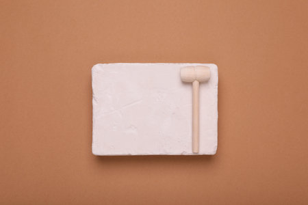 Educational toy for motor skills development. Excavation kit (plaster and wooden mallet) on brown...