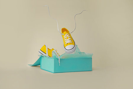 Box with pair of yellow classic old school sneakers on light gray backgroundの写真素材