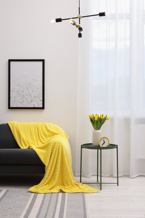 spring atmosphere. Stylish living room interior with comfortable furniture and bouquet of beautiful yellow tulipsの写真素材