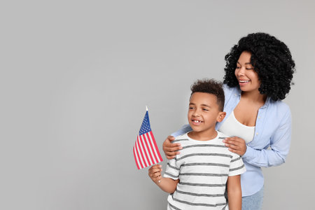 4th of July - Independence Day of USA. Happy woman and her son with American flag on light grey background, space for textの写真素材