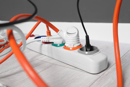 Power strip with different electrical plugs on white laminated floor indoors, closeupの写真素材