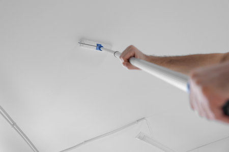 Handyman painting ceiling with roller, low angle view. Space for textの写真素材