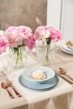 Stylish table setting with beautiful peonies and golden cutlery indoorsの写真素材