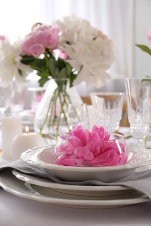 Stylish table setting with beautiful peonies in dining room, closeup. Space for textの写真素材