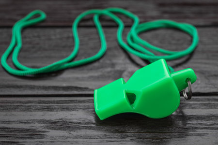 One green whistle with cord on wooden table, closeup. Space for textの写真素材