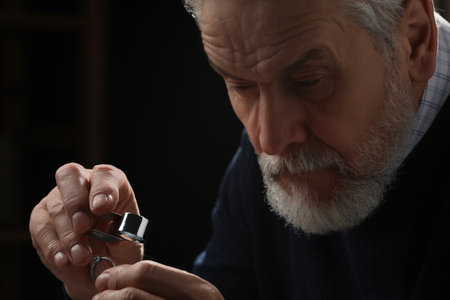 Professional jeweler working with ring on dark background, closeupの写真素材