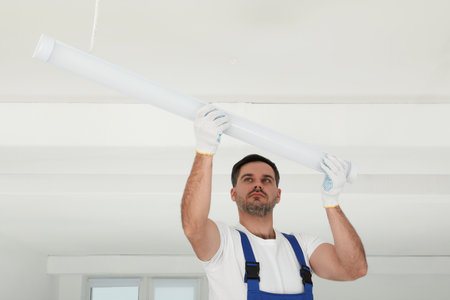 Electrician installing led linear lamp indoors. Ceiling lightの写真素材