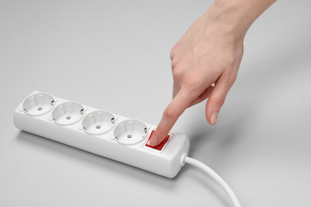 Woman pressing switch button of power strip on white background, closeupの写真素材