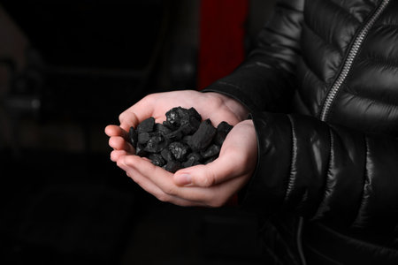 Woman with a handful of coal, closeup viewの写真素材