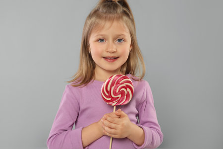 Portrait of happy girl with lollipop on light grey backgroundの写真素材