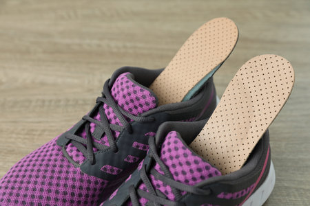Orthopedic insoles in shoes on floor, closeup