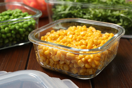 Containers with corn and fresh products on wooden table, closeup. Food storageの写真素材