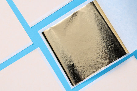 Edible gold leaf sheets on light blue background, flat layの写真素材