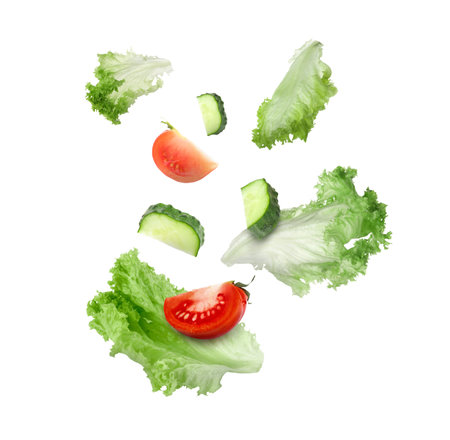 Lettuce leaves, cut cucumber and tomato falling on white backgroundの写真素材