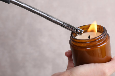 Woman lighting candle with gas lighter against gray wall, closeupの写真素材