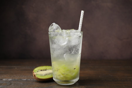 Glass of refreshing drink and cut kiwi on wooden tableの写真素材