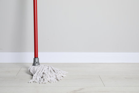 Mop with plastic handle near wall indoors. Space for textの写真素材