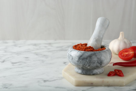 Red curry paste in mortar and ingredients on white marble table. Space for textの写真素材