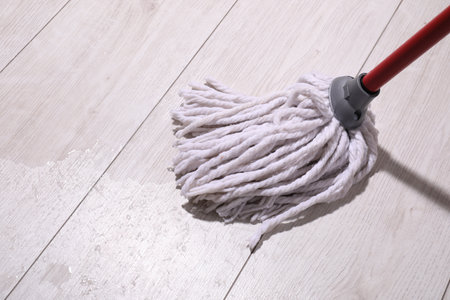 Cleaning dirty wooden floor with mop indoorsの写真素材