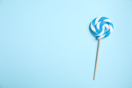 Stick with bright lollipop on light blue background, top view. Space for textの写真素材