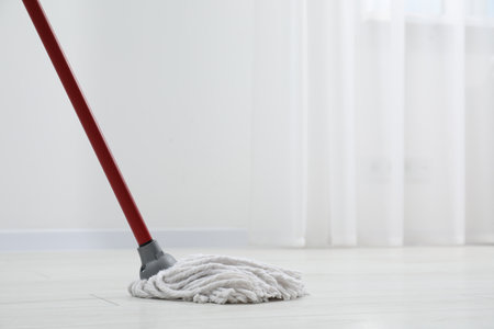 Cleaning dirty parquet floor with mop indoors. Space for textの写真素材