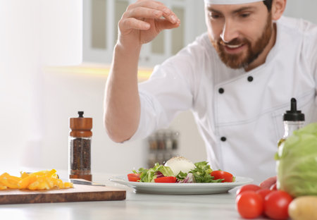 Professional chef salting delicious salad at marble table, focus on foodの写真素材