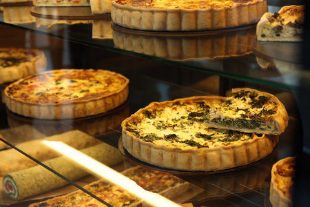Different delicious quiches on counter in bakery shop, closeup