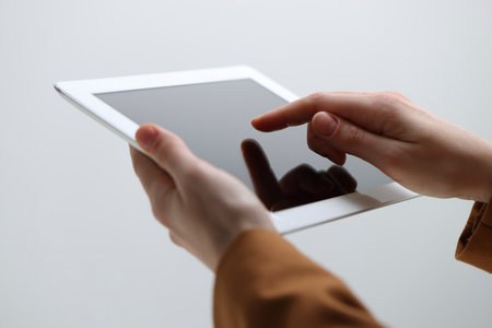Closeup view of woman using modern tablet on light gray backgroundの写真素材