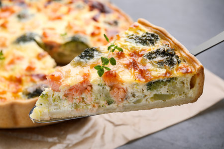 Spatula with piece of delicious homemade salmon quiche on light background, closeupの写真素材