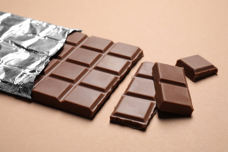 Pieces of delicious chocolate bar on beige backgroundの写真素材