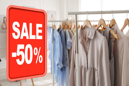 Sale sign and rack with collection of stylish women's clothes in modern boutiqueの写真素材